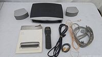 Photo of Bose GS Series II main unit, two satellite speakers, manual, remote, and cables arranged on a white table.