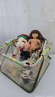 View of entire lot in vintage playpen with assorted dolls, toy sheep, and magazines.