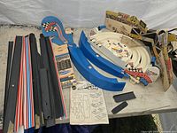 Thundershift 500 and Dukes of Hazzard slot car raceway parts on table, including boxed and loose components.