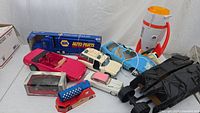 View of assorted toy cars including boxed Ford Mustang GT Concept, pink convertible, white classic cars, blue and pink convertibles, and a red remote control Corvette launcher.