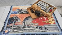HO and O gauge train sets displayed with Lionel baby blanket featuring train imagery