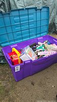 Photo showing the large purple plastic trunk open with assorted toys inside, including boxed Lego and various loose toys.