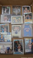 Top view of multiple basketball cards featuring David Lee, including rookie cards, autographed cards, and uniform patch cards, arranged in a box.