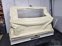 Front view of beige golf cart canopy cover with clear plastic window, fabric slightly wrinkled and marked.