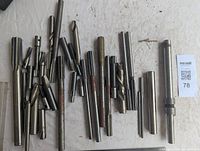 Photo depicting a collection of assorted milling cutters including multiple sizes and types with a ruler for scale.