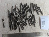 Photo showing multiple cylindrical metal milling cutters arranged next to a ruler for size reference, displaying their varying lengths and slot designs.