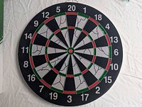 Front side of circular dart board on white fabric, showing numbers 1 to 20, black and white sections with green and red accents