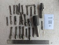 Top view of all milling cutters arranged with a ruler for scale. Includes very small to medium-sized cutters, some with multiple flutes.