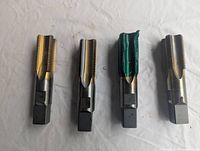 Four machine taps placed horizontally on white surface, showing their threading and shanks.