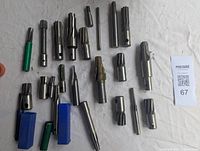 Photo showing an assortment of 23 milling cutters and reamers of different sizes and types on a white surface with two cutters in blue boxes and several with green caps.