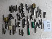 Overview of assorted milling cutters arranged on white cloth, showing variety of cutter sizes and types including some with yellow protective coating and green caps on shanks.
