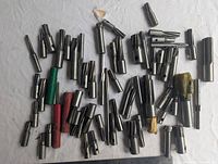 Photo showing a broad assortment of varied milling cutters laid out on a white surface, mostly metal with some protective colored sleeves.
