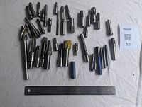 Top-down view of all milling cutters arranged around a ruler for scale, showing the variety of sizes and shapes.