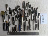 Image of the assorted milling cutters spread out with a ruler shown for scale, showing various sizes and types of cutters.