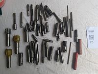 Photo showing a wide assortment of milling cutters, some with yellow plastic caps, spread out on a white surface.