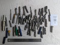Overview of approximately 40 assorted milling cutters arranged on white cloth with ruler for scale.