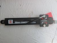 Black metal sway control bar with adjustment settings visible and attached lever, taken out of the box.