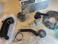 Overview of all components laid on counter including tub spout, handle, hardware, and Delta box.