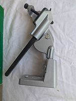 Side view of metal drill grinder attachment showing clamp base, adjustable arm, and screw clamp.