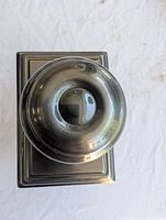 Front view of antique pewter round door knob with square rosette plate showing finish and minor dent.
