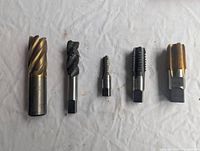 Five metal taps in a row showing various sizes and threading designs on a white surface