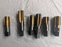 Front view of 6 metal threading taps arranged in a row on light fabric background, showing threaded cutting edges and square drive ends