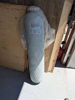 Full view of the wrapped resin tank standing upright in a storage area