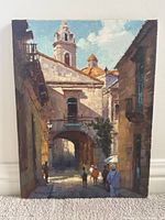 Full front view of oil painting on canvas showing European street scene with archway, buildings, and pedestrians.