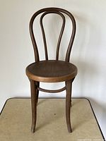 Front view of the antique bentwood cafe chair showing the rounded wooden seat and the bentwood backrest with distinctive oval bentwood loops.