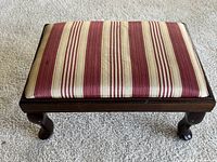 Top-down view of footstool showing striped red and beige upholstery with some staining.
