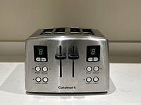 Front view of Cuisinart toaster showing dual digital displays, buttons for bagel, defrost, custom, and cancel, and two levers for slot controls.