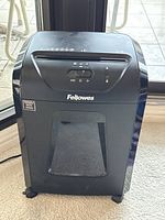 Front view showing the Fellowes logo, paper slot, and window on shredder bin.