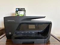 Front view of HP OfficeJet Pro 6978 showing the printer with the black HP 902XL ink cartridge box placed on top.