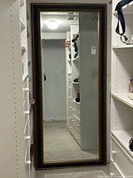 Full view of the large antique style full length mirror with ornate gold frame in a closet space.