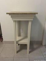 Front view of painted wood pedestal table without marble top showing legs, lower shelf, and upper frame