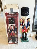 Photo of the nutcracker statue standing next to its original Kirkland box showing height and packaging.