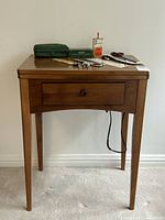 Closed wooden sewing table with small accessories on top