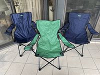 Three folded outdoor camping chairs, two navy blue and one green, showing overall design and condition.