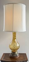 Full view of the vintage amber glass table lamp with off-white fabric shade showing overall height and design.