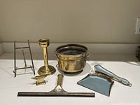 Overview of the entire lot showing the candlestick holder, crumb butler with brush, squeegee, anvil, and easel stand.