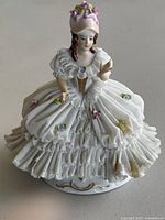 Front view of vintage Dresden porcelain lady figurine featuring delicate lace skirt and pastel floral accents.