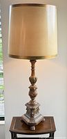 Full view of vintage table lamp showing carved wood base and fabric shade with gold trim.