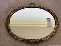 Front view of ornate oval gold framed mirror showing overall condition and shape.