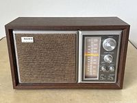 Front view of vintage Sony AM/FM radio with faux walnut cabinet, showing speaker grille and control panel.