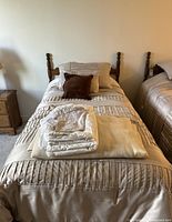 Full view of the prepared bed featuring the wooden headboard, metal bed frame, mattress and bedding with pillows and folded sheets.