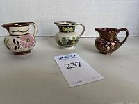Three English cream pitchers, hand-painted pottery, displayed side-by-side on white background with auction inventory card 237.