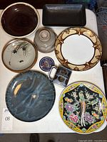 Top view of 8 ceramic and pottery dishes including plates, bowls and mug with varied colors and patterns.