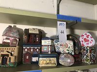 Photo showing an assortment of small decorative cloth boxes by Mary Morine and various small tins with colorful prints and house-themed designs