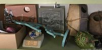 Shelf containing a green Fitz & Floyd ceramic pig bank, labeled Linarite mineral specimen, decorative tile, and teal blue carved dancing figure
