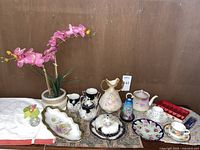 Full lot of decorative vintage and antique porcelain dishware, vases, and faux orchid plant.